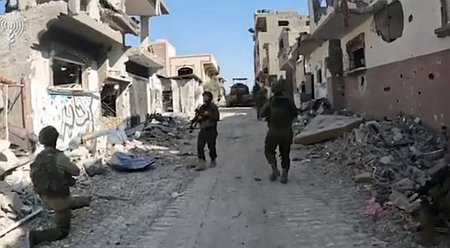 Israel soldiers move through a Gazan street