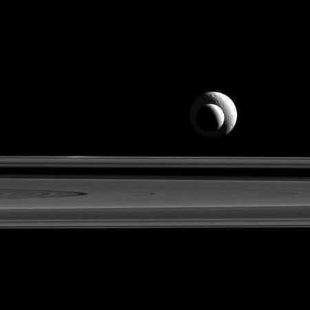 Two of Saturn's moons above its rings