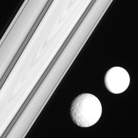 Mimas and second moon against Saturn's rings